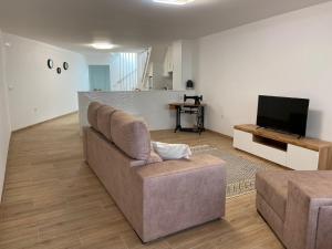 a living room with a couch and a television at Singer's Lounge in Porto de Mós