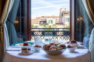 a table with plates of food on a table with a window at Ca' Bonfadini Historic Experience in Venice