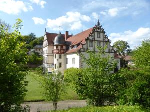 une grande maison blanche avec un toit marron dans l'établissement Schloss Buchenau, à Eiterfeld