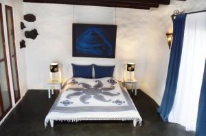 ein Schlafzimmer mit einem Bett und einem Gemälde an der Wand in der Unterkunft La 'Casita ALOE' Ferien in historischer Finca am Rande der Vulkane im schönen Dorf Uga in Uga