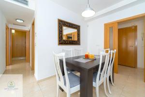 ein Esszimmer mit einem schwarzen Tisch und weißen Stühlen in der Unterkunft Bonito apartamento cerca de playa in El Campello + 22 Fotos