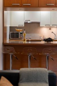 a kitchen with a counter with a microwave and two bar stools at Arriaga Residence I by An Island Apart in Funchal