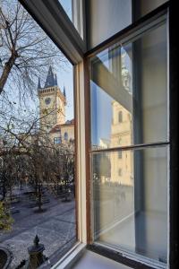 a window with a view of a building with a clock tower at Prague Days - Old Town Square Apartments in Prague