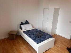 - une petite chambre avec un lit blanc et une couette bleue dans l'établissement Ferienwohnung im Herzen von Betzdorf, à Betzdorf
