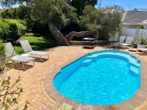 a swimming pool in a yard with chairs and a table at Anchor's Rest in Hermanus
