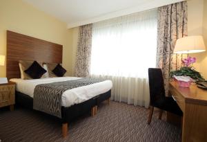 a hotel room with a bed and a desk and a window at Gresham Belson Hotel Brussels in Brussels