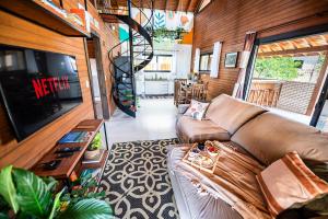 a living room with a couch and a tv at Cabana Perfeita a 800m da Praia - Lareira externa, Quintal Amplo, Pet Friendly, Ar condicionado, Netflix e Conforto completo in Imbituba