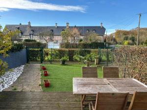 un tavolo in legno e sedie in un cortile di Les Douves Duplex 5 personnes lumineux avec jardin et terrasse aménagée , vue sur château à 5mn de la mer, proche Omaha Beach et Bayeux a Commes