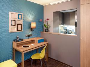 a room with a desk and a yellow chair at Aparthotel Adagio Köln City in Cologne
