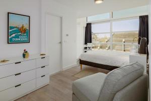 Un dormitorio blanco con una cama y una silla. en Nausicaa 0501 G, en Oostduinkerke