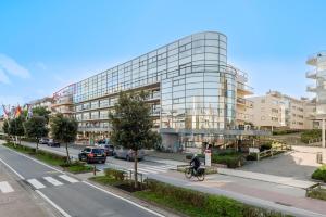 una persona montando una bicicleta delante de un edificio en Nausicaa 0501 G, en Oostduinkerke