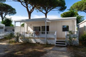 a white house with a tree in the background at Club del Sole Marina Family Resort in Punta Marina