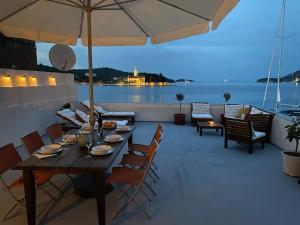 a wooden table with chairs and an umbrella on a patio at Waterfront House Carolina in Vis