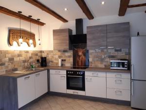 a kitchen with white cabinets and a refrigerator at Ferienhaus WeserLiebe in Bodenwerder