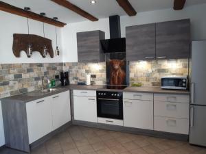 a kitchen with white cabinets and a dog on the wall at Ferienhaus WeserLiebe in Bodenwerder +19 photos