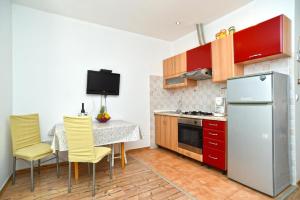 cocina con mesa, sillas amarillas y nevera en Cozy apartment with shared pool, en Valbandon