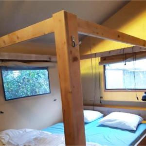 two bunk beds in a room with a window at Glampingtent 6 persoons Lindershoeve Bergeijk in Bergeijk