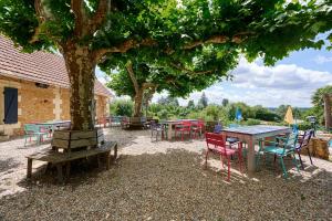 a group of tables and chairs under a tree at Glamping Dordogne in Douville