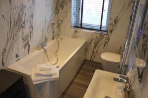 a bathroom with a sink and a tub and a toilet at The Boshaw Trout in Holmfirth