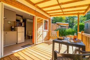 a patio with a table and a kitchen on a deck at Camping 4 étoiles Les Fougères in Rivedoux-Plage