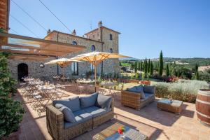 a patio with couches and tables and an umbrella at Podere Montale Winery in Seggiano