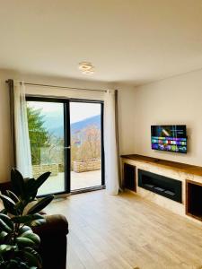ein Wohnzimmer mit einem TV und einem großen Fenster in der Unterkunft Stone Apartment with sauna Sinaia in Sinaia