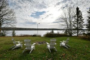 Tres sillas blancas sentadas en el césped cerca de un lago en Kenny Lodge Condo, en Namekagon 32 fotos más