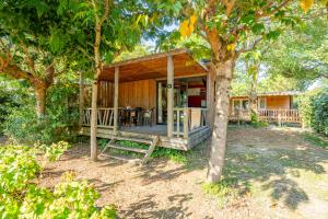 a wooden house with a porch in the woods at Camping 4 étoiles Les Fougères in Rivedoux-Plage