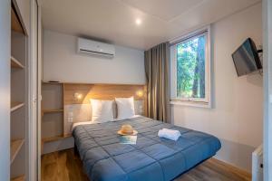 a hotel room with a blue bed with a hat on it at Camping 4 étoiles Les Fougères in Rivedoux-Plage +116 photos