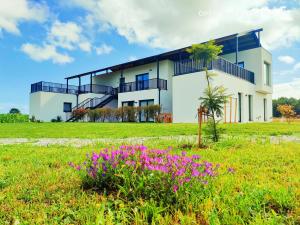 una casa blanca con flores púrpuras en un campo en Anam Cara House, en Serantes