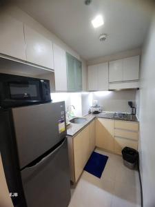 a small kitchen with a refrigerator and a sink at C1-7G Executive Studio with pool , 8boulevard Mactan Newtown in Lapu Lapu City