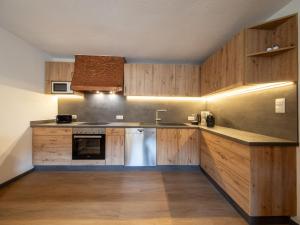kuchnia z drewnianymi szafkami, zlewem i zmywarką do naczyń w obiekcie Holiday Home Kleewein by Interhome w Solden