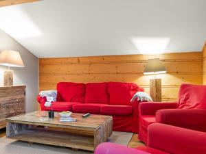 a living room with a red couch and a table at Apartment Fer à Cheval-3 by Interhome in Châtel +21 photos