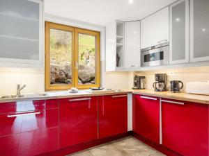 een keuken met rode kasten en een raam bij Apartment Fer à Cheval-2 by Interhome in Châtel