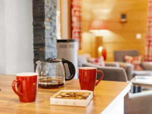 een tafel met twee kopjes en een waterkoker en een doos noten bij Apartment Fer à Cheval-2 by Interhome in Châtel