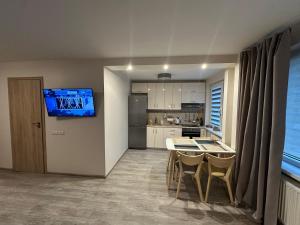 a kitchen with a table and a tv on a wall at Smiltės apartamentai in Birštonas