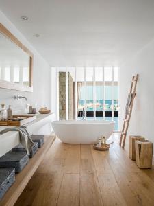 Un baño blanco con bañera y ventana. en Colonia Beach House, en Colonia de Sant Jordi