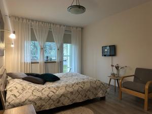 a bedroom with a bed and a chair and a window at Smiltės apartamentai in Birštonas
