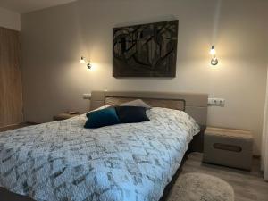 a bedroom with a bed with a blue pillow on it at Smiltės apartamentai in Birštonas +5 photos