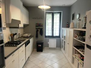 Appartement dans un vignoble في Chindrieux: مطبخ بخزائن بيضاء وفرن موقد