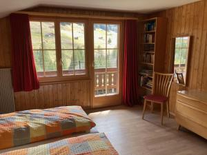 ein Schlafzimmer mit einem Bett und einem Stuhl und Fenstern in der Unterkunft Apartment Gilbachhöckli 2 by Interhome in Adelboden + 19 Fotos