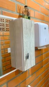 a cupboard with a coffee maker on a brick wall at Cantinho da Tia Dori in Rio Forcação