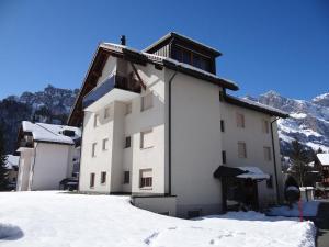 a white building in the snow with mountains in the background at Apartment Blumenweg 6 by Interhome in Engelberg