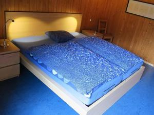 a bed with a blue comforter in a room at Apartment Chalet Heureka-Horbis by Interhome in Engelberg