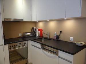 a kitchen with white cabinets and a black counter top at Apartment Seelenmattli by Interhome in Engelberg