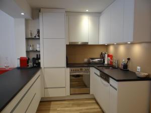 a kitchen with white cabinets and black counter tops at Apartment Seelenmattli by Interhome in Engelberg