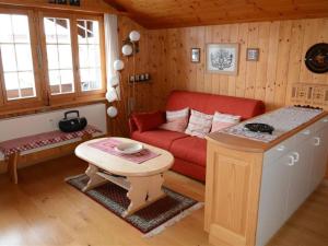 a living room with a red couch and a table at Apartment Résidence Sonnegg - Herrli by Interhome in Zweisimmen +10 photos