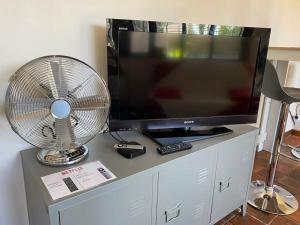 un ventilateur et une télévision sur un centre de divertissement dans l'établissement La cabane au fond du jardin, à Orléans