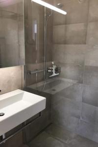 a bathroom with a shower and a white sink at Apartment Turmalin 2- Stock by Interhome in Lenk