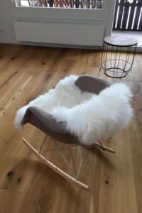 a white furry chair sitting on a wooden floor at Apartment Turmalin 2- Stock by Interhome in Lenk +14 photos